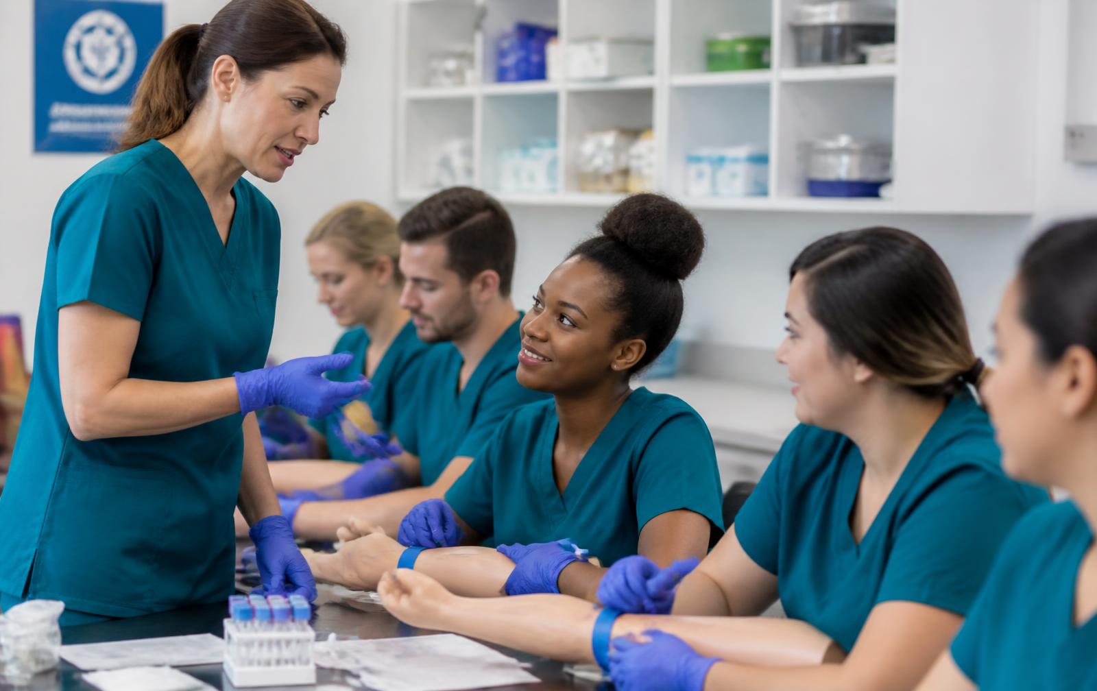 Phlebotomy instructor training students in a classroom lab